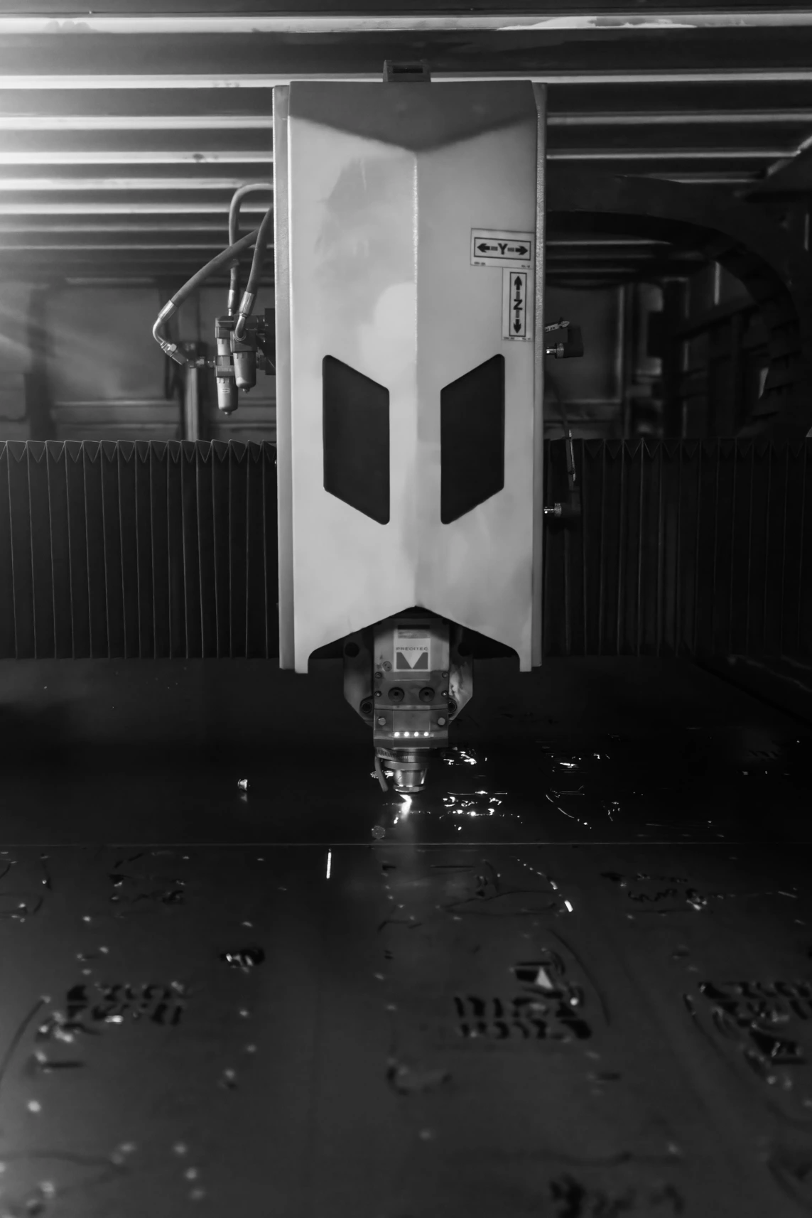 A black and white photo of a machine cutting metal, showcasing precision and industrial craftsmanship in action