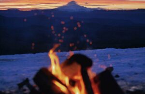 Close Up of a Fire in Winter with Mountains and Sunset in the Background